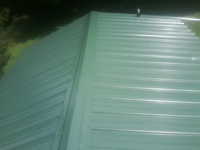 New green metal panels meeting at the ridge of a roof — Flat Roof Repair work by our crew in Templeton