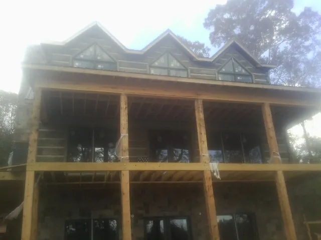 Dormers and porch framing on a large log home under construction — Roof Coating work by our crew in Templeton