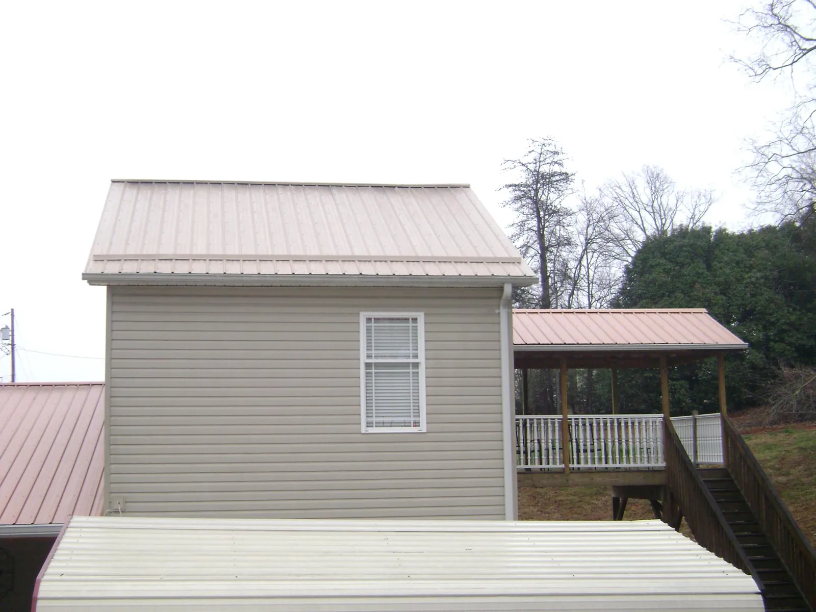 Tan metal roofs on a two story addition and attached porch, from a Roof Replacement job in Templeton