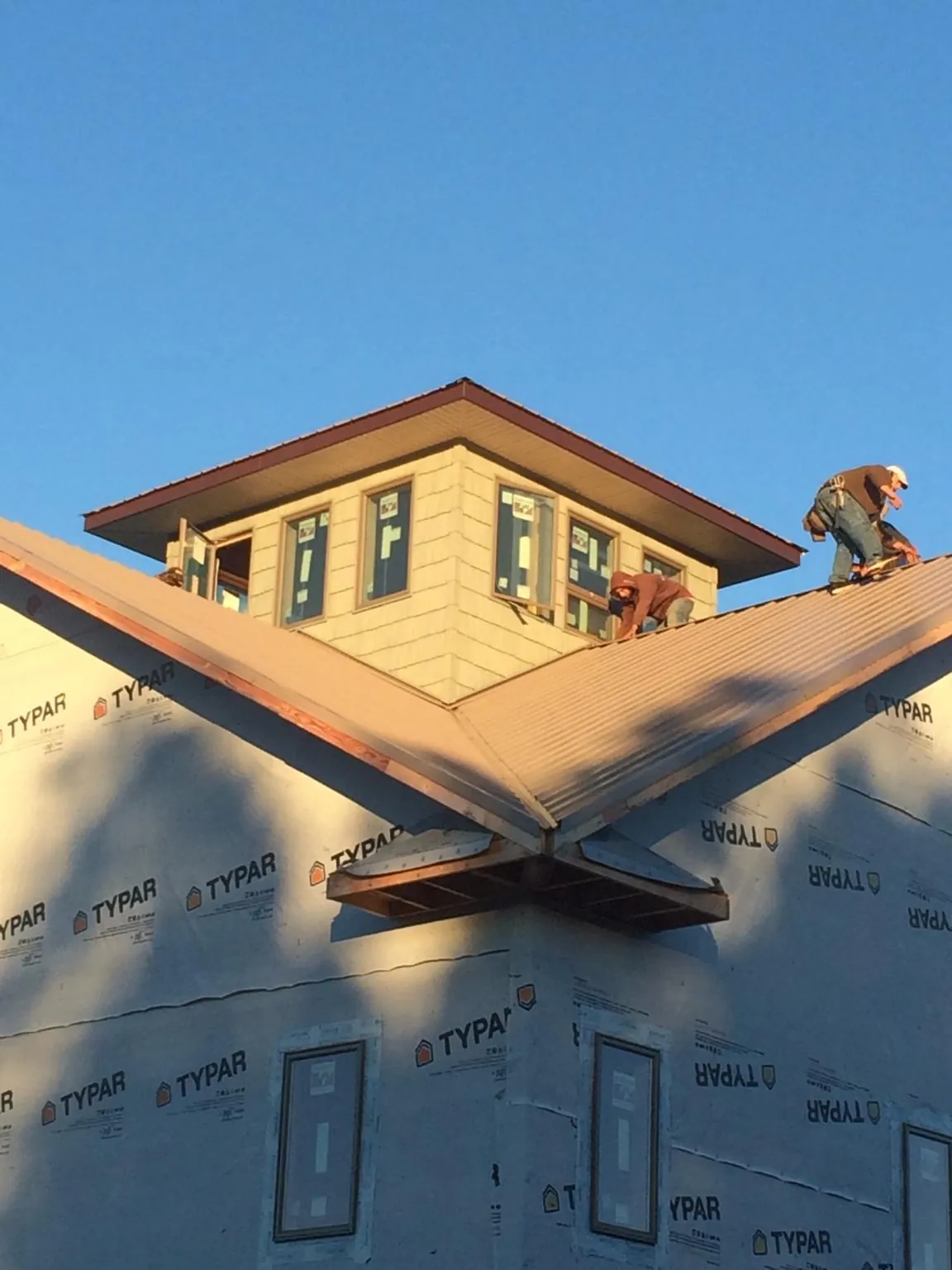 Roofers working around a rooftop cupola on a new metal roof at sunset — Roof Waterproofing in Templeton by Roofing Brothers
